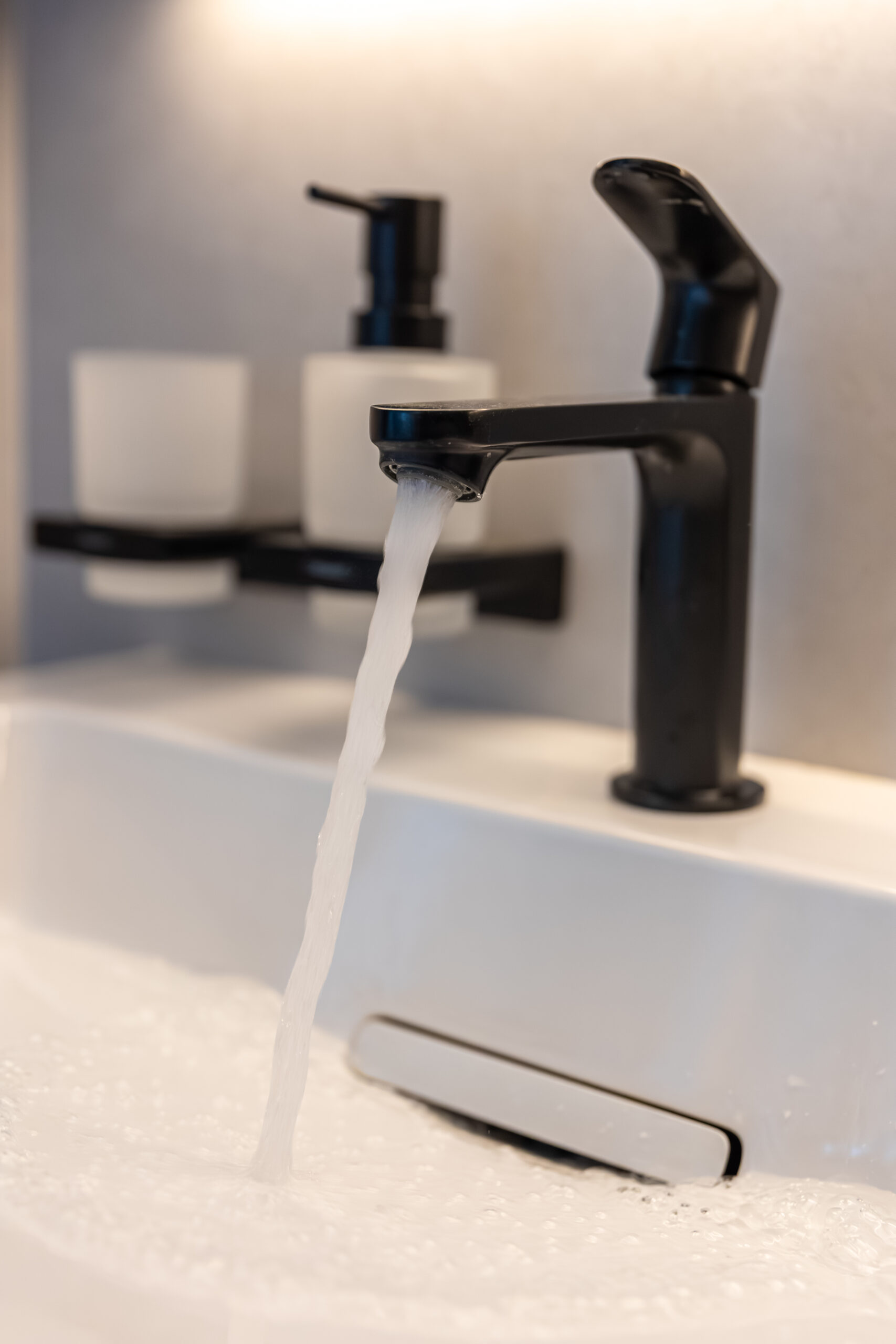 black faucet stream. foamy water. white basin